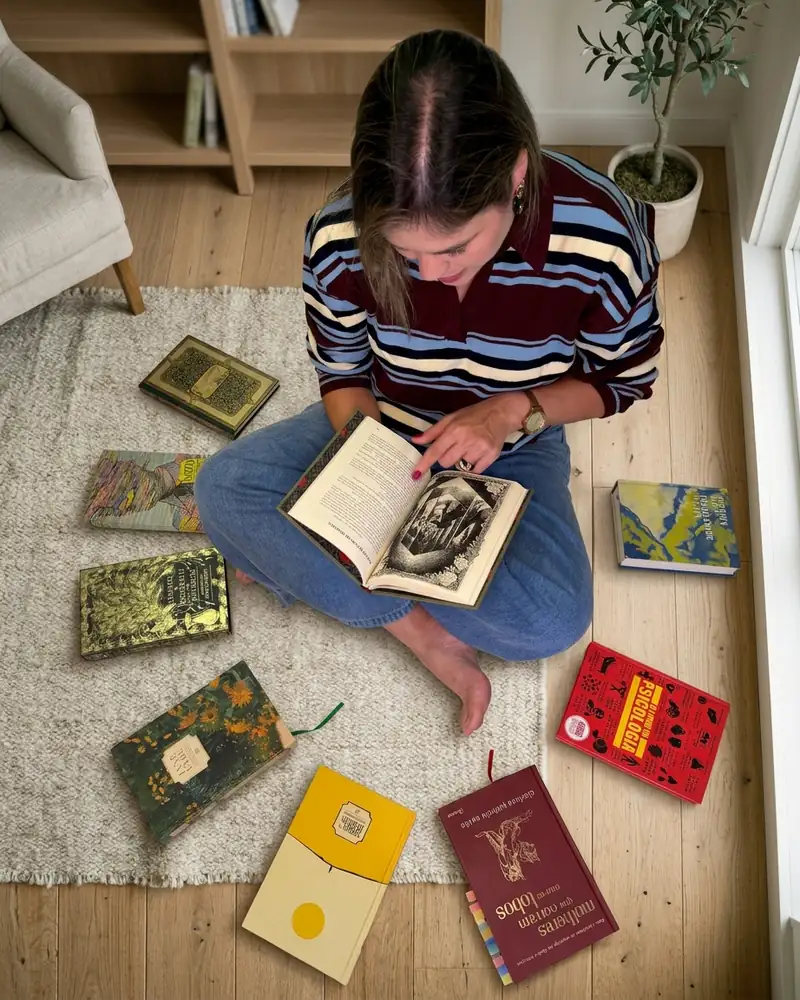Daniella Xavier sentada no chão, lendo, com livros ao redor